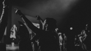 A black and white photo of people raising their hands at a concert.
