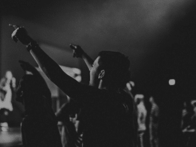 A black and white photo of people raising their hands at a concert.