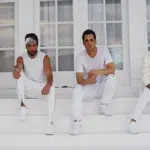 A group of men in white sitting on the steps of a house.