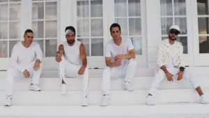 A group of men in white sitting on the steps of a house.