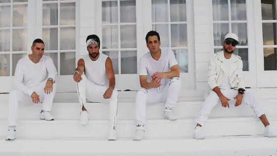 A group of men in white sitting on the steps of a house.