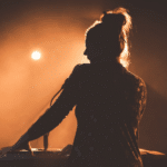 A silhouette of a woman playing a keyboard at a concert.