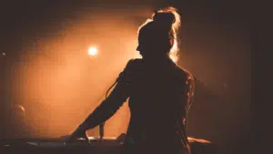 A silhouette of a woman playing a keyboard at a concert.