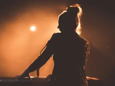 A silhouette of a woman playing a keyboard at a concert.