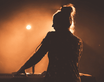 A silhouette of a woman playing a keyboard at a concert.