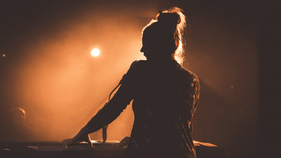 A silhouette of a woman playing a keyboard at a concert.