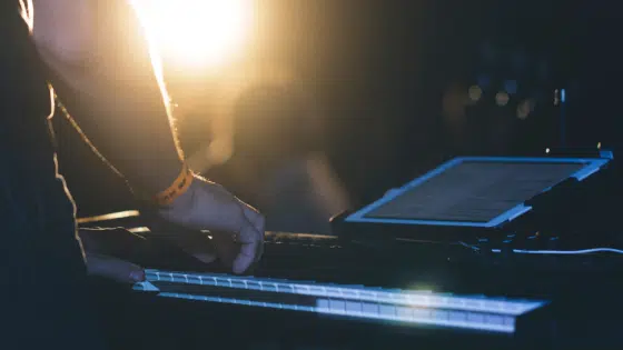 A person playing a keyboard in front of a light.