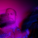 A man is standing in front of a purple light.