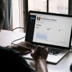 A man is working on a laptop in front of a keyboard.