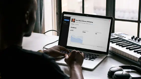 A man is working on a laptop in front of a keyboard.