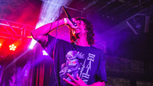 A man with dreadlocks singing into a microphone.