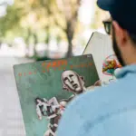 A man wearing a hat holding a book.