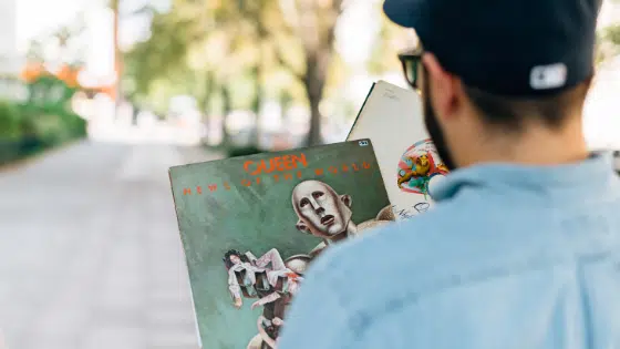 A man wearing a hat holding a book.