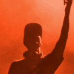 A silhouette of a man with his hands up in the air, representing freedom and expression.