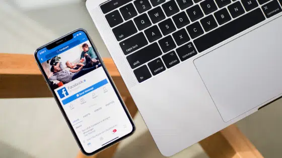 A laptop with a phone on it next to a wooden table.