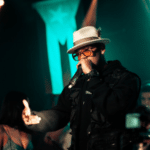 A man in a hat singing into a microphone.