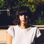 A woman in a white t - shirt sitting on the back of a truck.