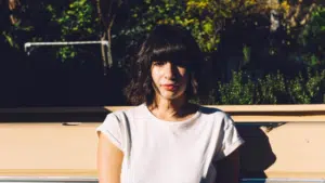 A woman in a white t - shirt sitting on the back of a truck.