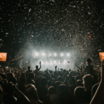 A crowd at a concert with confetti falling from the sky.