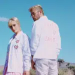 A man and woman standing in the desert wearing white jackets.