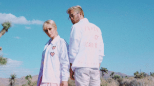 A man and woman standing in the desert wearing white jackets.