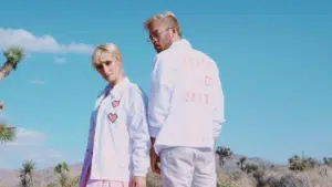 A man and woman standing in the desert wearing white jackets.