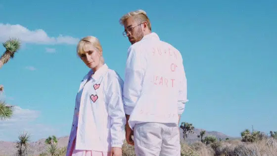 A man and woman standing in the desert wearing white jackets.