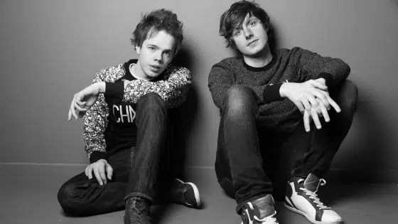 A black and white photo of two young men sitting on the floor.