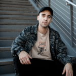 A man sitting on stairs wearing a camouflage jacket.