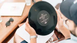 A man holding a vinyl record on a table.