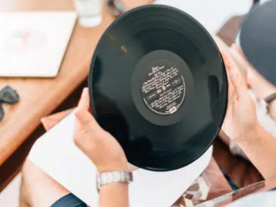 A man holding a vinyl record on a table.