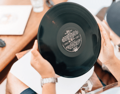 A man holding a vinyl record on a table.