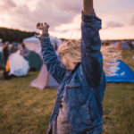 A woman raising her arms in the air at a music festival.