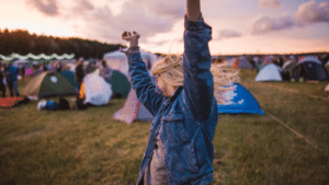 A woman raising her arms in the air at a music festival.