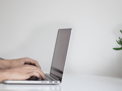 6 More Things Your Email Press Release Needs To Have A man typing on a laptop in front of a potted plant.