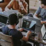 A group of people working on laptops at a table.