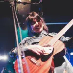 A woman playing an acoustic guitar on stage.