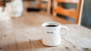 A white coffee mug sits on a wooden table.