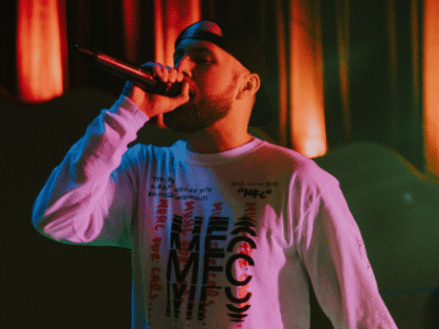 A man in a white shirt is holding a microphone.