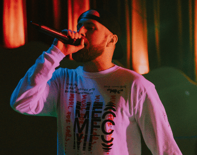 A man in a white shirt is holding a microphone.