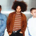 Three men with afro hair standing next to each other.