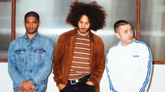 Three men with afro hair standing next to each other.