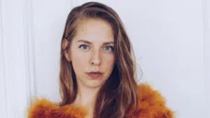 A young woman in an orange fur coat posing for a photo.