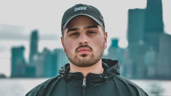 A man with a hat in front of a city skyline.