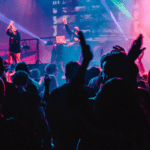 A crowd at a concert with their hands raised.