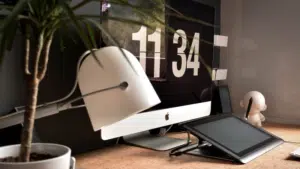 A desk with a monitor, keyboard, and a plant.