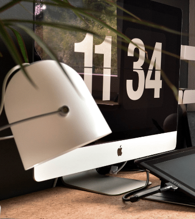 A desk with a monitor, keyboard, and a plant.