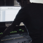 A man working on a mixing console in a recording studio.