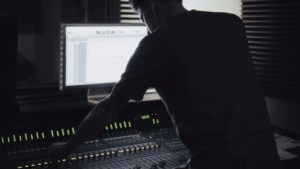 A man working on a mixing console in a recording studio.