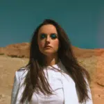 A woman in a white blazer standing in the desert.